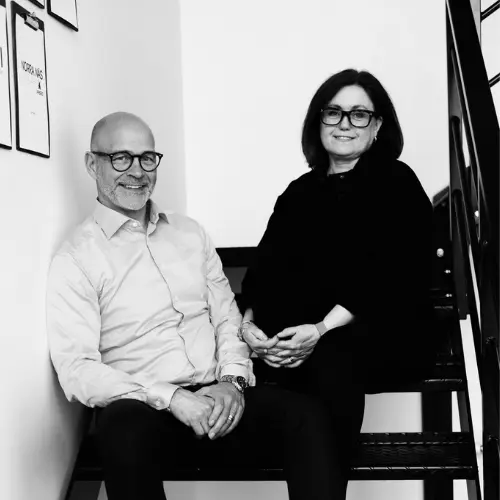 Mårten och Madeleine från KXM Management sitter på en trappa och ler mot kameran.